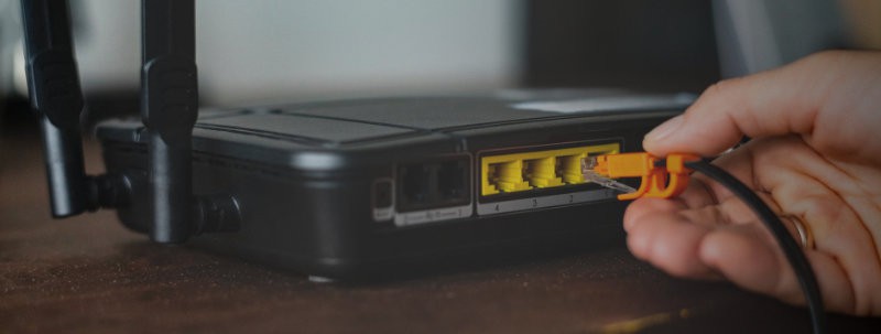 Iemand die een internetkabel in een modem plaatst.